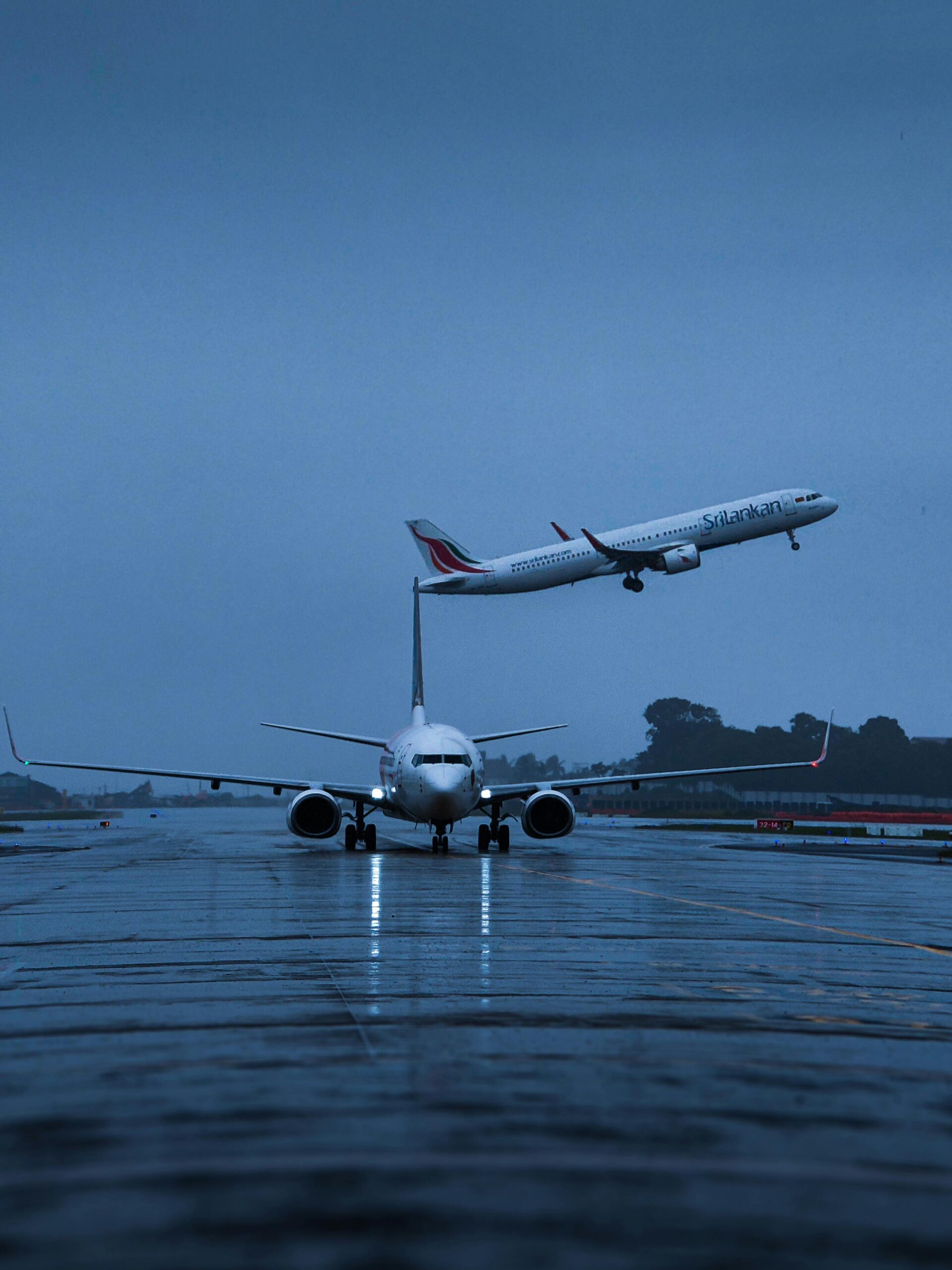 Airplanes on a rainy runway in Thiruvananthapuram, India, with one taking off.